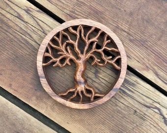 May include: A circular wooden carving of a tree of life with intricate details. The tree is brown and has a natural wood finish. The carving is set against a wooden background.