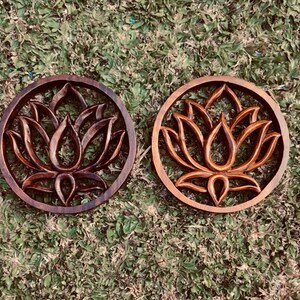 May include: Two dark brown wooden wall decor pieces with a carved lotus flower design.