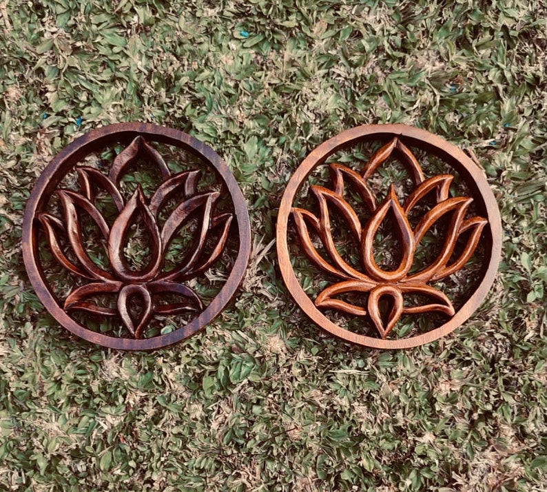 May include: Two dark brown wooden wall decor pieces with a carved lotus flower design.