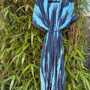 Peut inclure: Une robe longue ouverte sur le devant avec une fermeture &agrave; nouer &agrave; la taille et un motif tie-dye gris anthracite fonc&eacute; et bleu turquoise vif. Le v&ecirc;tement pr&eacute;sente des manches courtes et larges ainsi qu'une &eacute;tiquette noire au col avec le texte "Pirema" en dor&eacute;.