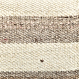 May include: Close-up of a woven rug with white and brown stripes. The rug is made of natural fibers and has a rough texture.