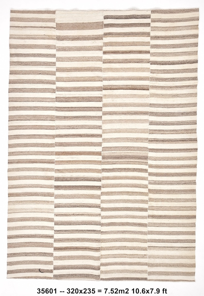 May include: A beige and brown striped rug with a geometric pattern. The rug is 10.6 feet by 7.9 feet and measures 320 centimeters by 235 centimeters.