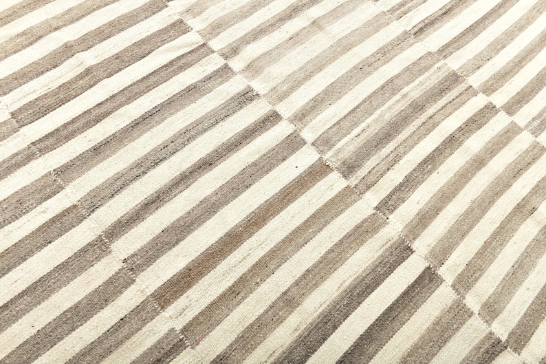 May include: A white and gray striped rug with a woven texture. The rug is made of natural fibers and has a rustic look.