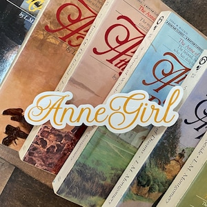 Può includere: Una pila di cinque libri tascabili con il titolo "Anne of" sulle copertine. I libri sono disposti a scalare, con il libro superiore leggermente spostato a destra. I libri sono tutti di colori diversi, il libro superiore è azzurro, il secondo libro è rosa chiaro, il terzo libro è verde chiaro, il quarto libro è marrone scuro e il quinto libro è blu scuro. I libri sono tutti in buone condizioni, senza danni o usura visibili. I libri fanno tutti parte della serie "Anne of" di L.M. Montgomery.