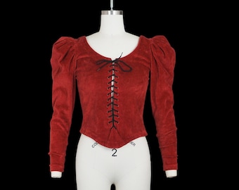 May include: A red velvet top with long sleeves and a lace-up front. The top has a round neckline and puffed shoulders.