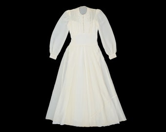 May include: A white long-sleeved dress with a lace collar and button closure. The dress has a full skirt and a gathered waist.