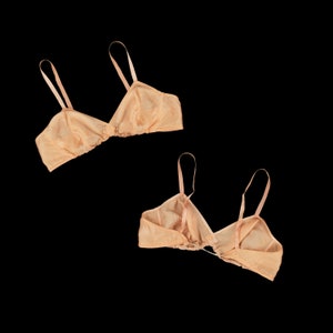 May include: Two peach-colored bras with adjustable straps. The bras are made of a soft, silky fabric and have a delicate, feminine design.