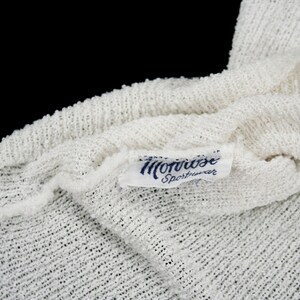 May include: White knitted fabric with a blue label that reads "Morrise Sportswear".