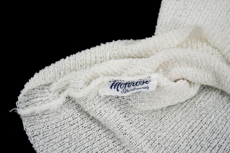May include: White knitted fabric with a blue label that reads "Morrise Sportswear".