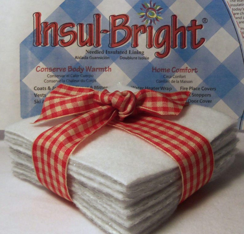 Pode incluir: Um pacote de quadrados de forro isolante acolchoado Insul-Bright brancos, amarrados com uma fita xadrez vermelha e branca. A embalagem mostra o nome da marca "Insul-Bright" e o texto "Conserve Body Warmth" e "Home Comfort".
