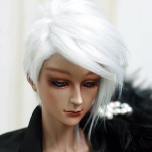 May include: A doll with a white wig styled in a short, choppy cut. The doll is wearing a black jacket with a black and white feathered collar.