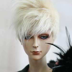 May include: A doll with a white, spiky wig and a black feather boa. The doll has blue eyes and is wearing a black jacket.