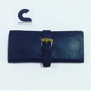 May include: A dark blue leather clutch with a gold buckle closure.