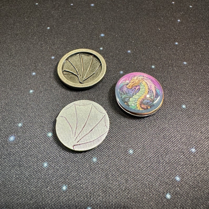 Wyrmspan dragon coins compared to the cardboard coin and metal coin for Wyrmspan. This is the coin sticker set by LaserLand.