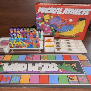 May include: A vintage board game titled "Magical Athlete" with a red box featuring cartoon characters. The game includes a colorful game board, player pieces, and other components. The game board says "Wild Weds".