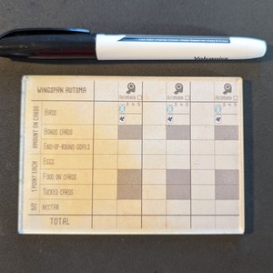May include: A brown and white Wingspan Automa scoring board with a grid for tracking points for birds, bonus cards, end-of-round goals, eggs, food on cards, tucked cards, and nectar. The board has a total score section at the bottom.