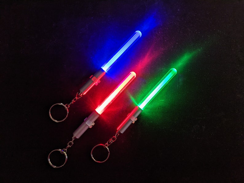 Peut inclure: Trois lampes de poche &agrave; cl&eacute;s lumineuses, chacune d'une couleur diff&eacute;rente : bleu, rouge et vert. Les lampes sont attach&eacute;es &agrave; des porte-cl&eacute;s argent&eacute;s.