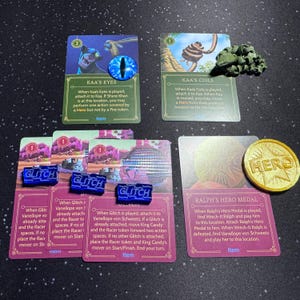 May include: A set of game cards and tokens for the Wreck-It Ralph video game. The cards feature characters like Kaa, Vanellope, and Wreck-It Ralph. The tokens are blue and gold.