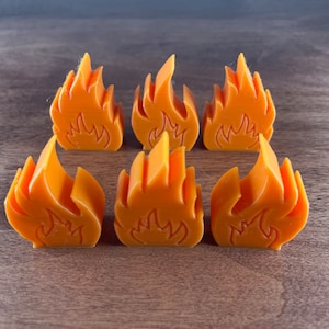 May include: Six orange flame-shaped candle holders made of wax. The candle holders are all the same size and shape, and they are arranged in a row.