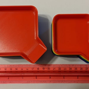 Top view of the two different sized stackable game trays shown alongside a red ruler so they can be measured.
