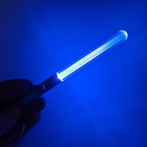 Peut inclure: Un b&acirc;ton lumineux bleu avec une source de lumi&egrave;re blanche. Le b&acirc;ton lumineux est tenu dans une main.
