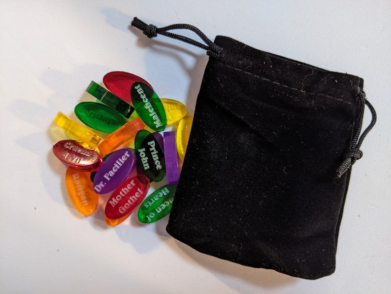 Disney Villainous random tokens (28) with their velvet bag to help choose a random villain to play. Shown alongside the velvet bag.
