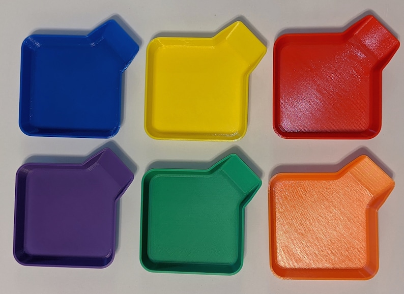 Top view of rainbow stackable token trays fanned out showing all six colors including yellow, green, blue, and purple.