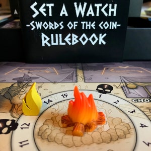 May include: A close-up of a game board with a yellow and orange flame token. The board has a skull, numbers, and the words "Set a Watch - Swords of the Coin - Rulebook".