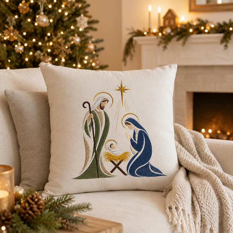May include: A square off-white throw pillow featuring an embroidered nativity scene. The design depicts a figure in a green robe holding a staff, a figure in a blue robe kneeling, and a baby in a golden manger beneath a yellow star.