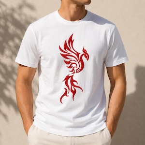 May include: A white short-sleeved t-shirt featuring a prominent red embroidered phoenix design centered on the chest. The phoenix is depicted with stylized, flowing wings and a long, flame-like tail, creating a bold contrast against the plain white fabric.