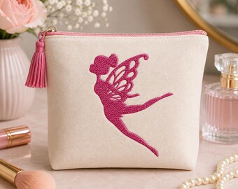 May include: A cream-colored canvas zippered pouch featuring a dark pink embroidered fairy silhouette on the front. The pouch includes a matching pink tassel attached to the zipper pull, providing a decorative accent to the simple fabric design.