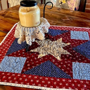 May include: A white ceramic mug with a black handle and the text "But First, Coffee" in a black, handwritten-style font. The mug is on a white surface.