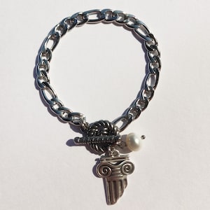 Puede incluir: Un brazalete de cadena de plata con un dije de plata que presenta una perla y un diseño de columna estilizado.