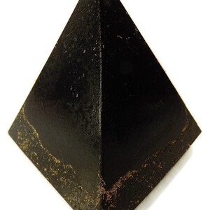 May include: A black pyramid-shaped object with a smooth, dark surface and a textured, weathered base. The four triangular faces meet at a sharp apex, and the bottom edges show a rough, granular, and brownish-gold distressed finish.