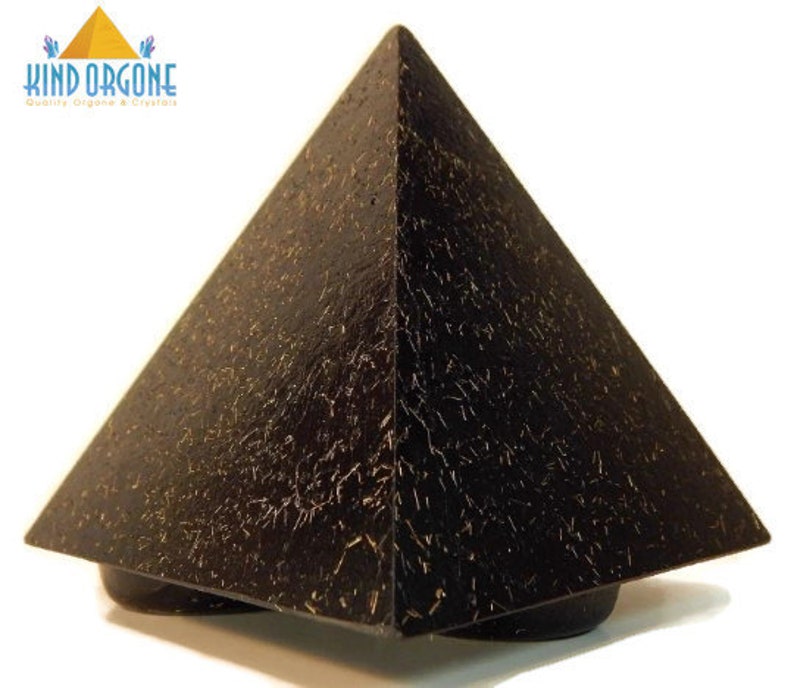 May include: A black pyramid-shaped object with a textured surface featuring fine, light-colored, hair-like inclusions throughout. The top left corner displays a logo with a yellow pyramid icon and the text KIND ORGONE Quality Orgone & Crystals.