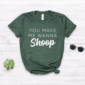 May include: A dark green t-shirt with the text "You make me wanna Shoop" in white lettering.
