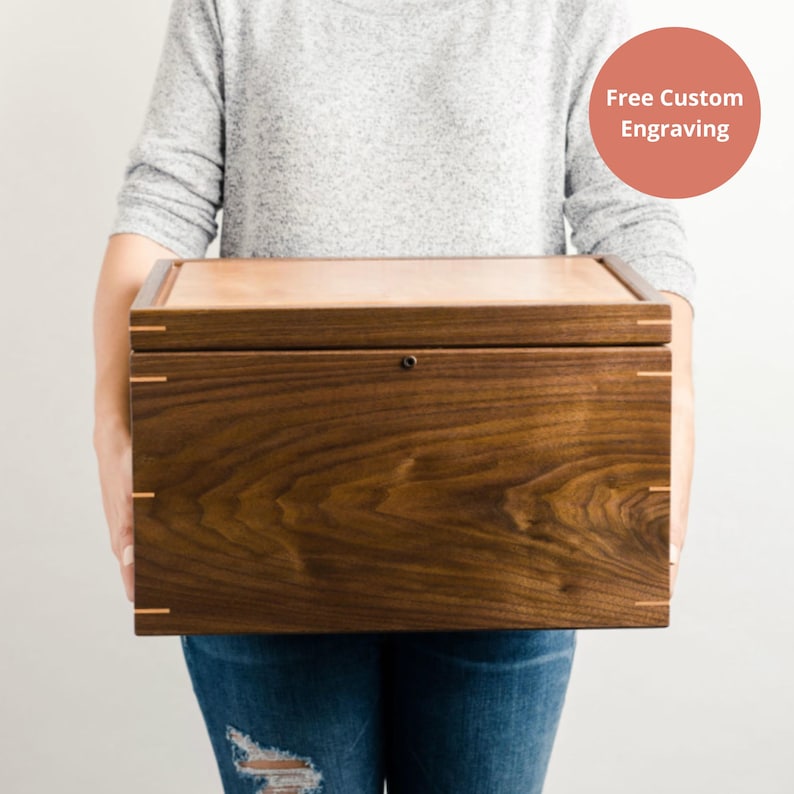 Person holding a closed walnut keepsake box with cherry lid and miter joinery, free custom engraving available