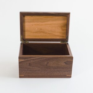 Open handcrafted walnut keepsake box with a cherry wood lid panel, showing spacious interior storage and fine joinery, perfect for memory preservation or custom gift giving.