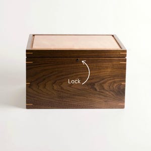 Closed walnut keepsake box with cherry lid and visible lock feature marked by arrow