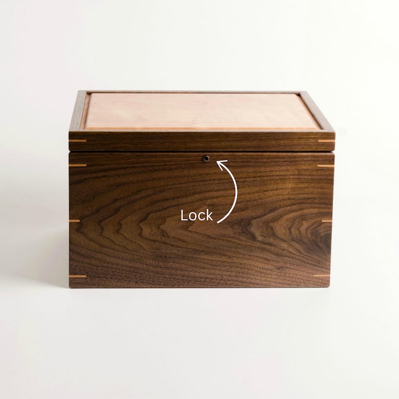 Closed walnut keepsake box with cherry lid and visible lock feature marked by arrow