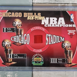 May include: A red and white Chicago Bulls NBA Champions card with a red floor patch. The card features the team's six NBA championship trophies from 1991, 1992, and 1993.