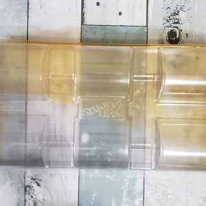 May include: A clear plastic storage case with six compartments. The case is labeled "Stampin' Up!" and has a gold trim.