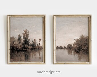 May include: Two framed landscape paintings in a muted colour palette. Both paintings depict a river scene with trees and a cloudy sky. The frames are a light wood colour.