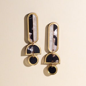 A pair of black, white and gold acrylic statement dangle earrings.