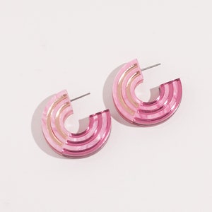 A pair of pink acrylic statement hoop earrings.