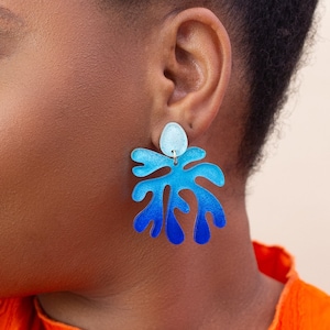 A model wearing a pair of ombre blue Matisse statement dangle earrings.