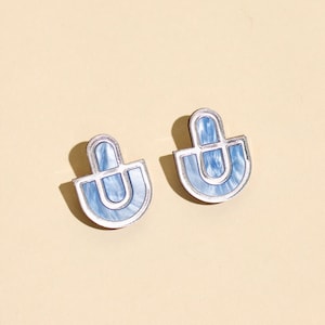 A pair of blue and silver statement stud earrings.