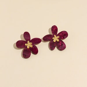 A pair of plum purple acrylic statement flowers earrings.