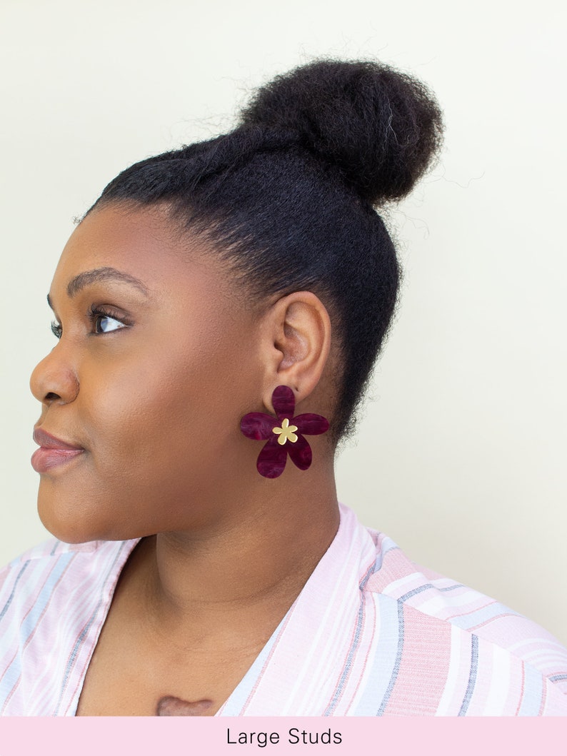 A model wearing a pair of plum purple acrylic statement flower earrings in the size Large