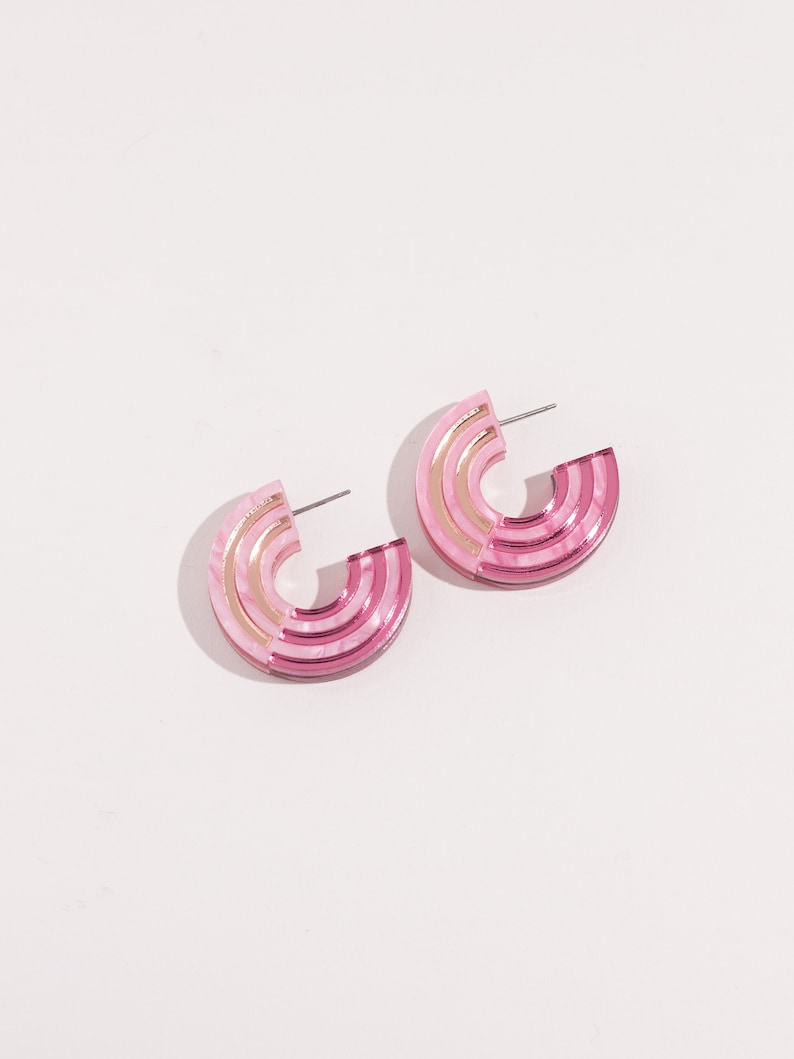 A pair of pink acrylic statement hoop earrings.